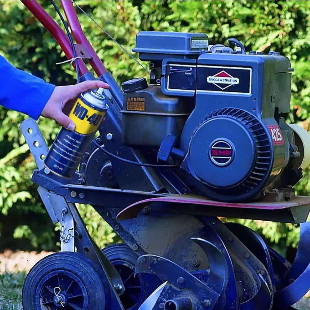 Alt Tag: Applicazione di WD-40 su motore macchina da giardino