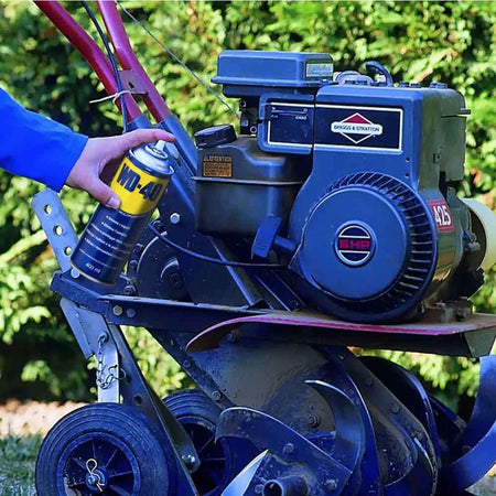 Alt Tag: Applicazione di WD-40 su motore macchina da giardino